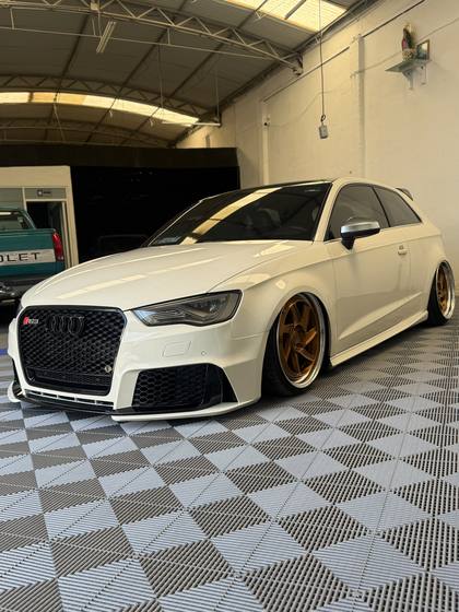 Audi RS3 blanco con rines dorados dentro del taller