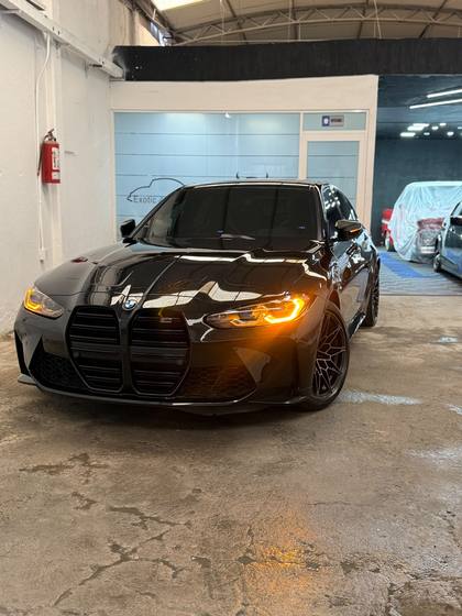 BMW M3 negro con los faros encendidos dentro del taller