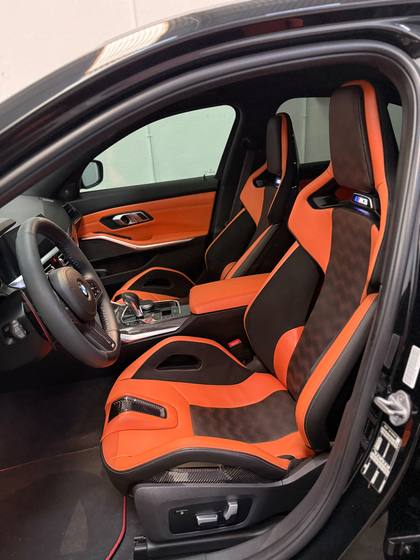 Interior de BMW M3 con asientos deportivos en naranja y negro