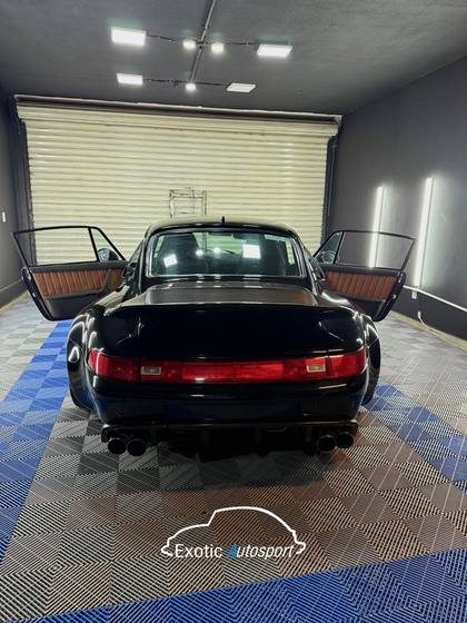 Porsche 993 negro con las puertas abiertas dentro del taller