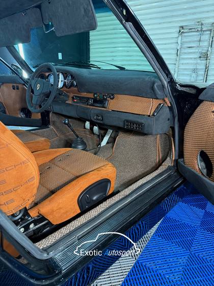Interior de Porsche 993 con la puerta abierta y asientos en gamuza tabaco