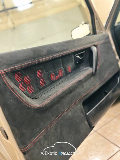Panel de puerta forrado en alcántara con costura roja y bocinas a la vista