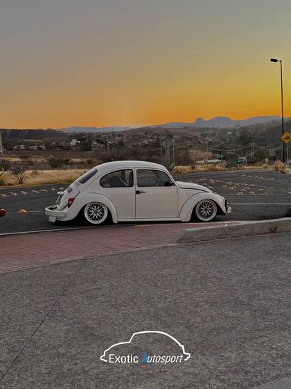 Volkswagen sedán blanco con rines BBS al atardecer