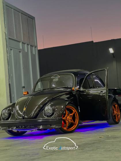 Volkswagen sedán negro con rines naranjas dentro del taller